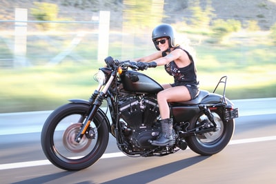 戴着黑色和灰色摩托车头盔的妇女白天骑着黑色和银色巡洋舰摩托车
